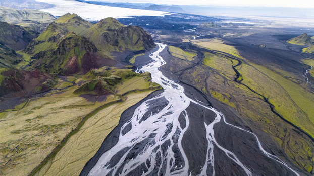 Aerial view of the braided river flowing through the dramatic green mountains and volcanic landscape of Thakgil near Vik Myrdalshreppur Iceland.