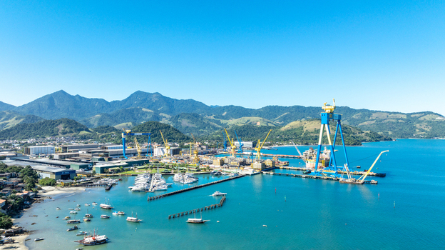 Aerial view of the BrasFELS shipyard and marina featuring large industrial cranes numerous boats moored in the turquoise bay and lush green mountains in Angra dos Reis Rio de Janeiro Brazil.