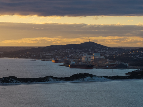 Aerial view of the port of Albany near Torndirrup National Park with cargo ships docked at the industrial waterfront under a golden sunset sky in Albany Western Australia Australia. Aerial view of the port of Albany near Torndirrup National Park with cargo ships docked at the industrial waterfront under a golden sunset sky in Albany Western Australia Australia.