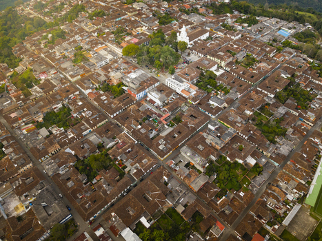 Aerial view of terracotta roofs stretch across the landscape punctuated by the bright white church steeple and lush green trees Salamina Caldas Colombia.