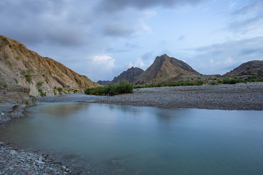 Aerial view of the serene flowing river cuts through the rugged rocky landscape contrasting the soft water with the harsh mountains Pakistan.