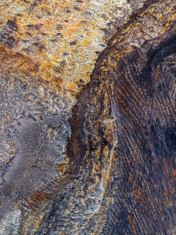 Aerial view of an open pit mine showcasing layered rock formations and mineral deposits in the rugged terrain of Iceland. Aerial view of an open pit mine showcasing layered rock formations and mineral deposits in the rugged terrain of Iceland.