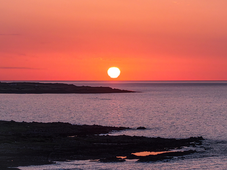 Aerial view of a vibrant sunset over the sea with rocky coastline and calm waters in Newcastle Northern Ireland United Kingdom. Aerial view of a vibrant sunset over the sea with rocky coastline and calm waters in Newcastle Northern Ireland United Kingdom.