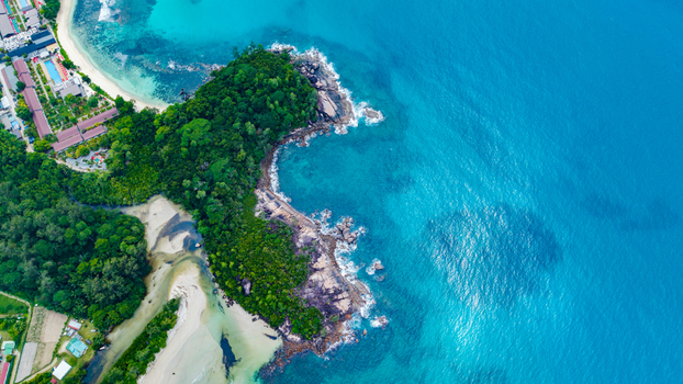 Aerial view of Grand Anse Mahe coastline featuring a rocky headland covered in lush tropical vegetation a sandy beach and clear turquoise ocean waters in Grand Anse Mahe Seychelles. Aerial view of Grand Anse Mahe coastline featuring a rocky headland covered in lush tropical vegetation a sandy beach and clear turquoise ocean waters in Grand Anse Mahe Seychelles.