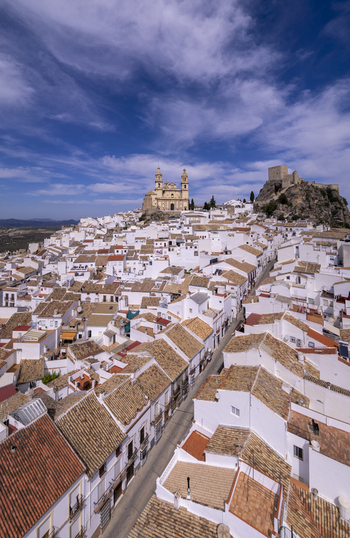 Aerial view of the white washed town of Olvera with its historic church and castle perched on a hilltop under a bright blue sky in Olvera Andalusia Spain. Aerial view of the white washed town of Olvera with its historic church and castle perched on a hilltop under a bright blue sky in Olvera Andalusia Spain.