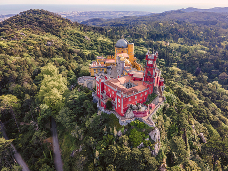 Aerial view of Pena Palace a colourful Romanticist castle building on hilltop during a beautiful sunset Sintra Lisbon Portugal.