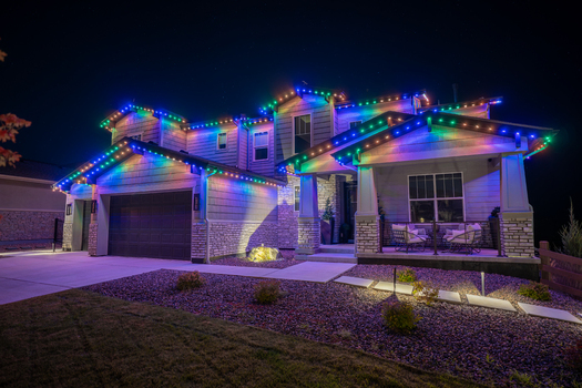 View of a suburban house illuminated with colorful LED roofline lighting at night featuring stone and siding architecture with a front porch in Aurora Colorado United States. View of a suburban house illuminated with colorful LED roofline lighting at night featuring stone and siding architecture with a front porch in Aurora Colorado United States.