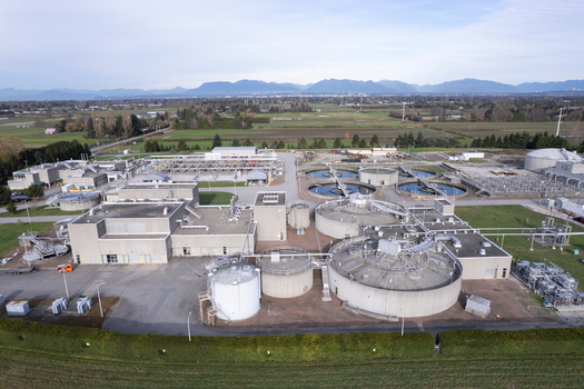 Aerial view of Lulu Island Wastewater Treatment Plant with circular sedimentation tanks industrial buildings and surrounding green fields in Richmond British Columbia Canada. Aerial view of Lulu Island Wastewater Treatment Plant with circular sedimentation tanks industrial buildings and surrounding green fields in Richmond British Columbia Canada.