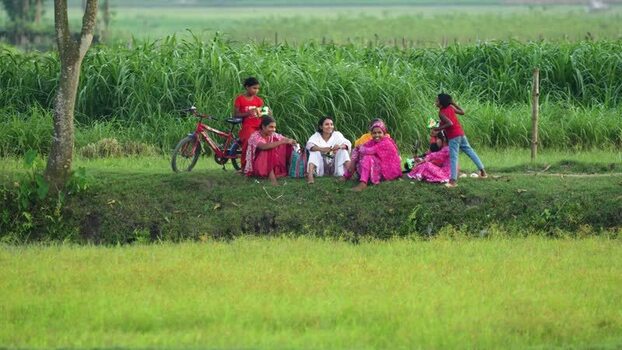 View of women and children sitting in a rural field Bangladesh.