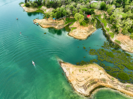 Rangamati Hill District Bangladesh 18 May 2024 Aerial view of Kaptai Lake with small boats navigating the turquoise water surrounded by lush green hills and forested shorelines.
