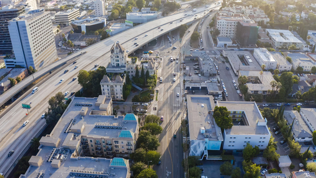 Aerial view of a busy urban landscape featuring a highway overpass residential and commercial buildings and city streets in Los Angeles California United States.