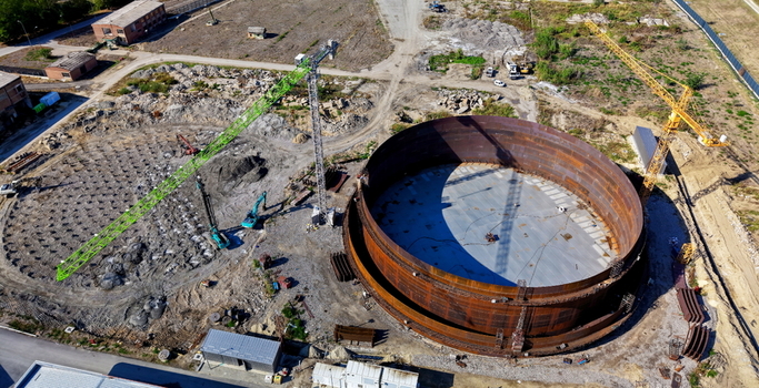 Aerial view of the assembly of a large refinery oil storage tank at a construction site with cranes heavy machinery and metal structures in Kovin Vojvodina Serbia. Aerial view of the assembly of a large refinery oil storage tank at a construction site with cranes heavy machinery and metal structures in Kovin Vojvodina Serbia.