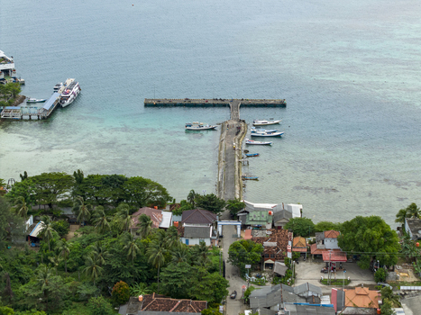 Aerial view of the Karimunjawa ferry harbour pier extending into the turquoise sea lined with boats under a soft sky Karimunjawa Jawa Tengah Indonesia. Aerial view of the Karimunjawa ferry harbour pier extending into the turquoise sea lined with boats under a soft sky Karimunjawa Jawa Tengah Indonesia.