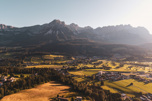 Aerial view of the Wilder Kaiser mountain range rising above the lush green valleys meadows and small villages of Wilder Kaiser Tirol Austria. Aerial view of the Wilder Kaiser mountain range rising above the lush green valleys meadows and small villages of Wilder Kaiser Tirol Austria.