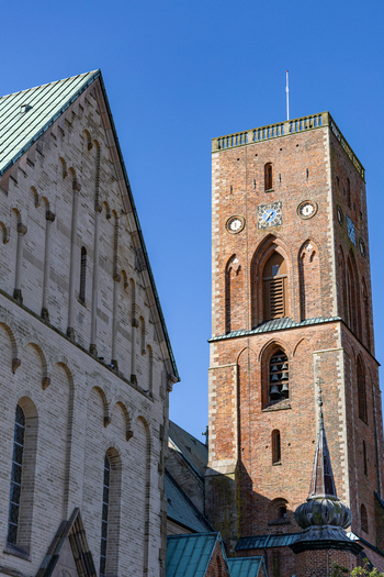 View of Ribe Cathedral featuring the historic red brick bell tower and stone facade under a clear blue sky in Ribe Denmark. View of Ribe Cathedral featuring the historic red brick bell tower and stone facade under a clear blue sky in Ribe Denmark.