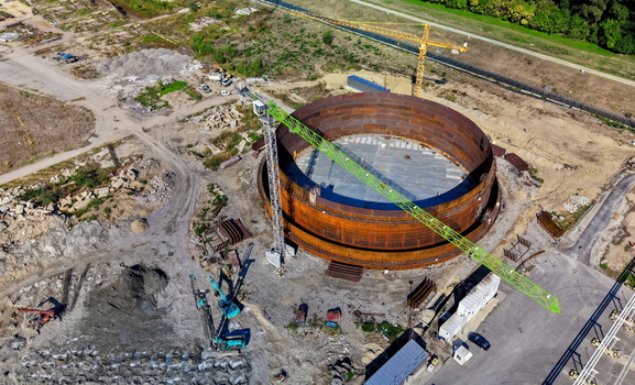 Aerial view of the assembly of a large cylindrical oil storage fuel tank at a refinery construction site featuring a prominent green crane Kovin Vojvodina Serbia. Aerial view of the assembly of a large cylindrical oil storage fuel tank at a refinery construction site featuring a prominent green crane Kovin Vojvodina Serbia.
