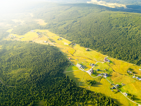 Aerial view of Jizerka village nestled in a lush green valley surrounded by dense coniferous forests and rolling meadows under warm golden hour light in Korenov Liberec Region Czechia. Aerial view of Jizerka village nestled in a lush green valley surrounded by dense coniferous forests and rolling meadows under warm golden hour light in Korenov Liberec Region Czechia.