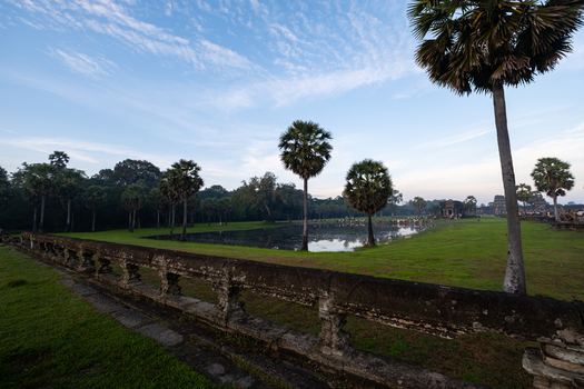 View of Angkor Wat temple complex with a reflecting pond palm trees and stone balustrade in Krong Siem Reap Siem Reap Province Cambodia.
