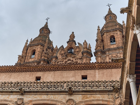 Salamanca Spain 29 November 2025 View of the ornate Baroque towers and facade of La Clerecia and Iglesia del Espiritu Santo with intricate stone carvings under a cloudy sky.