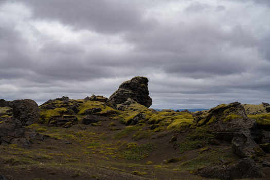 View of moss covered volcanic rocks punctuate the stark landscape under a dramatic sky where earth meets the heavens in a symphony of gray and green Skaftárhreppur Iceland. View of moss covered volcanic rocks punctuate the stark landscape under a dramatic sky where earth meets the heavens in a symphony of gray and green Skaftárhreppur Iceland.