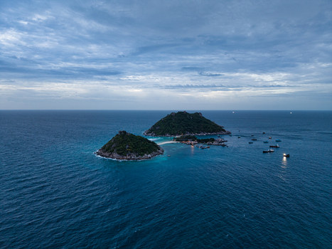 Aerial view of the islands of Ko Nang Yuan with turquoise water rocky shores and lush green vegetation under a cloudy sky in Ko Tao Surat Thani Thailand.