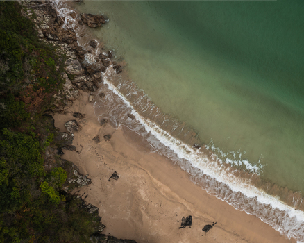Aerial view of Xilloi Beach featuring turquoise waters crashing onto golden sand beside lush green cliffs in Vicedo Lugo Spain. Aerial view of Xilloi Beach featuring turquoise waters crashing onto golden sand beside lush green cliffs in Vicedo Lugo Spain.