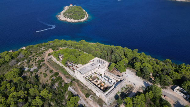 Aerial view of Fort George surrounded by lush pine trees on a hill overlooking the blue sea and a small island Vis Splitsko dalmatinska Croatia. Aerial view of Fort George surrounded by lush pine trees on a hill overlooking the blue sea and a small island Vis Splitsko dalmatinska Croatia.