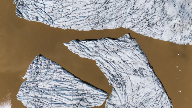 Aerial view of glacial ice formations float in the muddy waters of Hoffellsjokull creating a striking contrast between the stark white ice and the earth toned water Hoffellsjokull Iceland. Aerial view of glacial ice formations float in the muddy waters of Hoffellsjokull creating a striking contrast between the stark white ice and the earth toned water Hoffellsjokull Iceland.