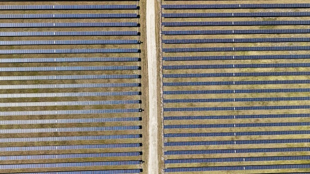 Aerial view of rows of solar panels stretch across the landscape bisected by a pale path capturing the contrast between technology and nature Elkton Florida United States. Aerial view of rows of solar panels stretch across the landscape bisected by a pale path capturing the contrast between technology and nature Elkton Florida United States.