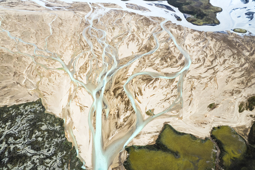 Aerial view of the intricate braided glacial river patterns of the F208 road area with turquoise water flowing through volcanic sand and green moss Icelandic Highlands Iceland. Aerial view of the intricate braided glacial river patterns of the F208 road area with turquoise water flowing through volcanic sand and green moss Icelandic Highlands Iceland.