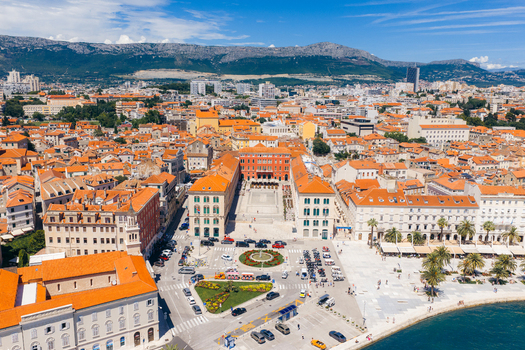 Aerial view of Republic Square surrounded by historic red roofed buildings and the waterfront promenade under a clear sky in Split Split Dalmatia County Croatia. Aerial view of Republic Square surrounded by historic red roofed buildings and the waterfront promenade under a clear sky in Split Split Dalmatia County Croatia.