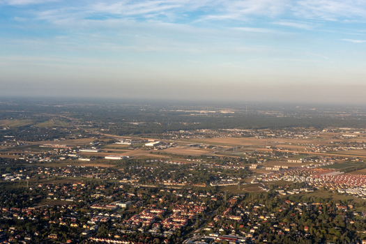 Aerial view of rooftops and verdant trees stretch across the landscape under a soft hazy sky Warsaw Masovian Voivodeship Poland. Aerial view of rooftops and verdant trees stretch across the landscape under a soft hazy sky Warsaw Masovian Voivodeship Poland.