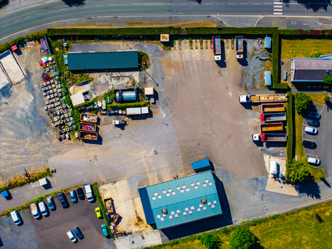 Aerial view of an industrial yard featuring a large warehouse parked trucks construction materials and various vehicles in Rocroi Grand Est France. Aerial view of an industrial yard featuring a large warehouse parked trucks construction materials and various vehicles in Rocroi Grand Est France.
