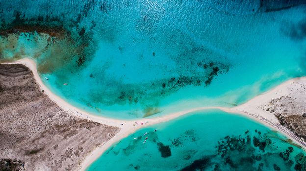 Aerial view of Los Roques archipelago featuring a sandbar connecting two islands in turquoise waters with boats and people on the beach Los Roques Dependencias Federales Venezuela. Aerial view of Los Roques archipelago featuring a sandbar connecting two islands in turquoise waters with boats and people on the beach Los Roques Dependencias Federales Venezuela.