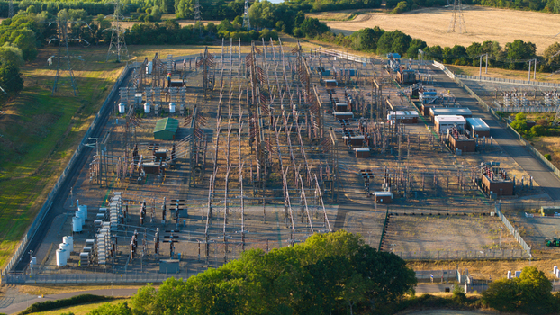 Aerial view of Grendon national grid station with electrical transformers switchgear and power lines inside a fenced perimeter near rural fields in Northampton England United Kingdom. Aerial view of Grendon national grid station with electrical transformers switchgear and power lines inside a fenced perimeter near rural fields in Northampton England United Kingdom.