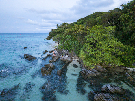 Aerial view of turquoise waters meet rocky shores fringed by lush greenery creating a stunning coastal contrast Karimunjawa Central Java Indonesia. Aerial view of turquoise waters meet rocky shores fringed by lush greenery creating a stunning coastal contrast Karimunjawa Central Java Indonesia.