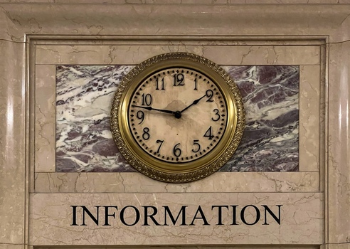 View of the iconic gold rimmed analog clock at the Grand Central Terminal information booth set against a marble wall in New York New York United States. View of the iconic gold rimmed analog clock at the Grand Central Terminal information booth set against a marble wall in New York New York United States.