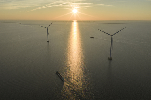 Aerial view of offshore wind turbines and a cargo ship on the calm sea during a golden sunset Netherlands. Aerial view of offshore wind turbines and a cargo ship on the calm sea during a golden sunset Netherlands.