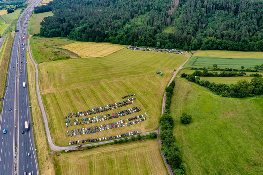 Geiselwind Germany 20 June 2025 Aerial view of the Heroes Festival Geiselwind parking area with rows of cars in a green field next to a busy highway and dense forest.