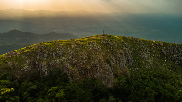 Aerial view of Mt. Gemi with its summit cross rocky terrain and lush green vegetation illuminated by golden hour light in Amedzofe Volta Region Ghana. Aerial view of Mt. Gemi with its summit cross rocky terrain and lush green vegetation illuminated by golden hour light in Amedzofe Volta Region Ghana.