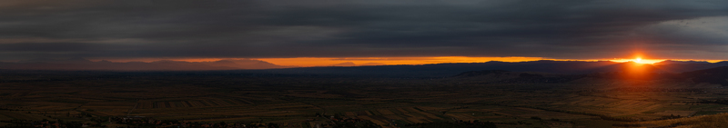 View of a panoramic sunset over the rolling hills and agricultural fields of Mereni Covasna County Romania. View of a panoramic sunset over the rolling hills and agricultural fields of Mereni Covasna County Romania.