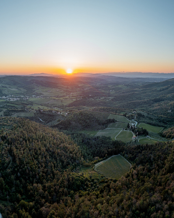 Aerial view of the rolling hills and vineyards of Greve in Chianti at sunset with lush forests and golden light illuminating the landscape in Greve in Chianti Tuscany Italy.