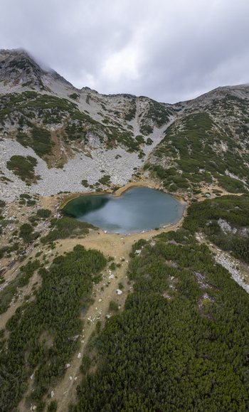 Aerial view of Muratovo Lake in Pirin National Park surrounded by rocky slopes alpine vegetation and a winding trail in Blagoevgrad Province Bulgaria. Aerial view of Muratovo Lake in Pirin National Park surrounded by rocky slopes alpine vegetation and a winding trail in Blagoevgrad Province Bulgaria.