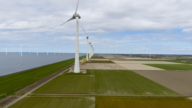 Aerial view of a line of wind turbines standing along a dike separating the water from agricultural fields in Espel Flevoland Netherlands. Aerial view of a line of wind turbines standing along a dike separating the water from agricultural fields in Espel Flevoland Netherlands.