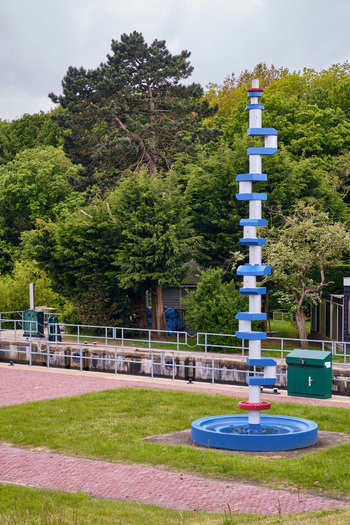 Wieringerwerf Netherlands 17 May 2026 View of the Gemaal Leemans monument a tall blue and white sculpture standing against a backdrop of lush green trees under an overcast sky.