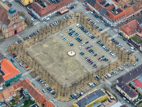 Aerial view of the grand Place d Armes a symmetrical square bustling with parked cars and surrounded by historic buildings Neuf Brisach Grand Est France.