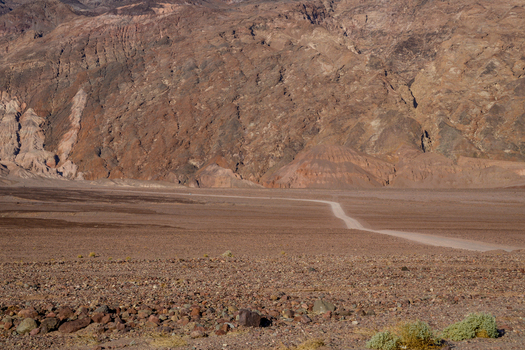 View of a dirt road winding through the arid rocky desert landscape of Death Valley National Park s backcountry with rugged mountains in the background Death Valley California United States.