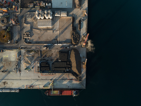 Aerial view of the industrial port area with a cargo ship docked cranes and storage silos in Augusta Sicily Italy. Aerial view of the industrial port area with a cargo ship docked cranes and storage silos in Augusta Sicily Italy.