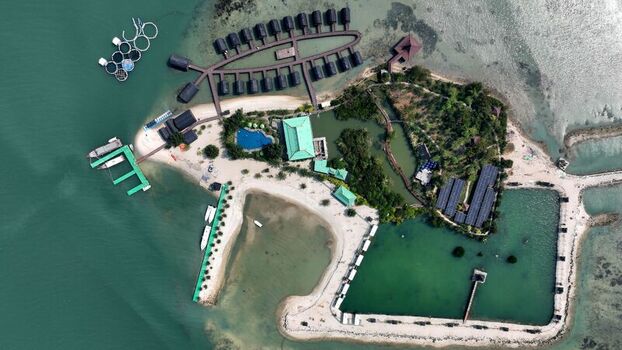 Aerial view of Pulau Lima Resort featuring overwater bungalows a swimming pool and a pier surrounded by turquoise waters in Kasemen Banten Indonesia. Aerial view of Pulau Lima Resort featuring overwater bungalows a swimming pool and a pier surrounded by turquoise waters in Kasemen Banten Indonesia.