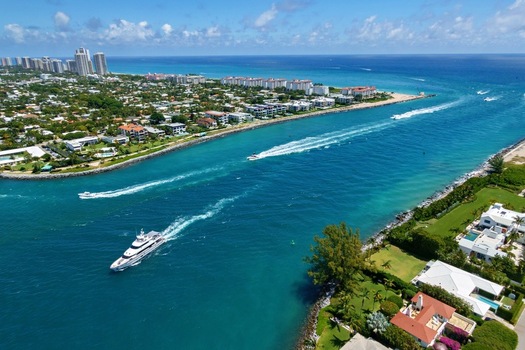 Aerial view of Palm Beach Inlet with luxury yachts cruising through turquoise waters past waterfront mansions and lush greenery Palm Beach Florida United States. Aerial view of Palm Beach Inlet with luxury yachts cruising through turquoise waters past waterfront mansions and lush greenery Palm Beach Florida United States.